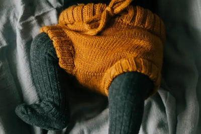 A baby wearing orange knitted shorts.