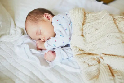 Baby sleeps in a crib with its American made cotton blanket made in Georgia. 