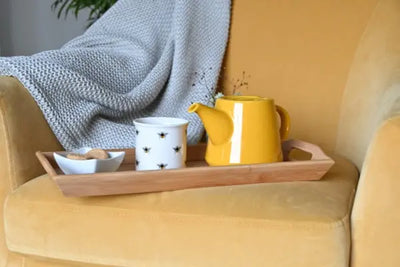 A table coaster holds a tea kettle and mug for drinks.