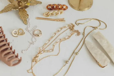 Unique, artisan and handcrafted jewelry sit on a table. There are American made necklaces, earrings, and rings. 