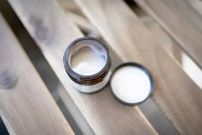 A brown table with an open container of moisturizer and lip balms that were made in America. 