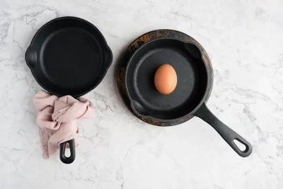 Two skillets sitting on pot pads and holders.