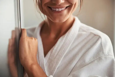 A woman wearing a comfortable robe showcasing the soft fabric and design. She stands very cozy in the room knowing her perfectly knitted robe was made in America. 