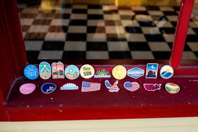 Colorful stickers on a windowsill, featuring designs like the sun, maps, and American flags. 