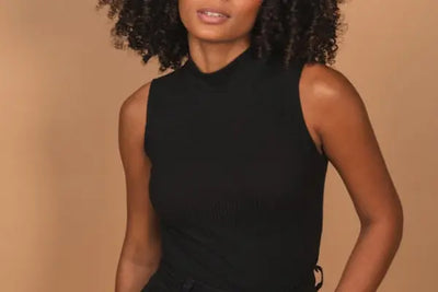 A woman wearing a black tank top made in America with 100% organic cotton.