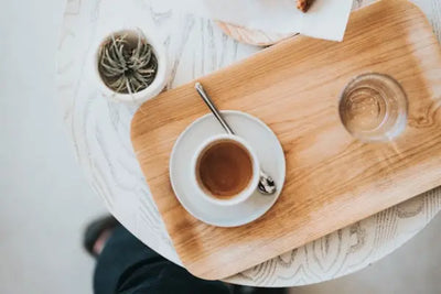 A wooden tray with a glass and mug sitting on it.