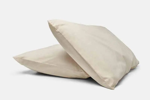 Two light beige pillows with American Blossom Linens Natural Cotton Bed Pillowcases are stacked together on a white background.