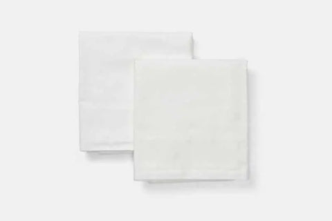 Two Natural Cotton Bed Pillowcases by American Blossom Linens, elegantly folded, are displayed side by side on a plain white background.