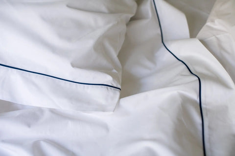 Close-up of the Cotton Piping Design Bed Sheet Set by American Blossom Linens, featuring USA-grown cotton sheets and pillowcases with elegant dark blue piping for a crisp, clean look.