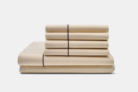 A neatly folded Cotton Piping Design Bed Sheet Set by American Blossom Linens, made from luxurious USA-grown cotton, is stacked on a plain white background.