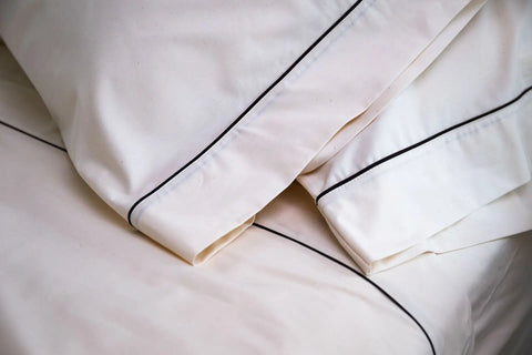 Close-up of American Blossom Linens Cotton Piping Design Bed Sheet Set, featuring cream-colored, USA-grown cotton sheets and pillowcases with elegant black piping that adds comfort, cleanliness, and luxury to your bedroom.