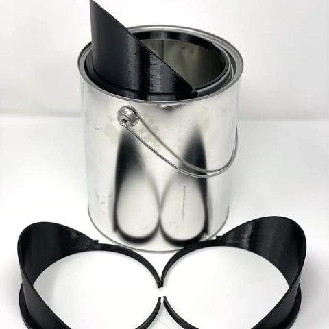 A quart-sized metal paint can from Chatelet Manufacturing holds a coiled black strip, while two curved black pourers from the 3-Pack Quart Paint Pourer Value Pack are displayed in front on a white surface. No more spills!.