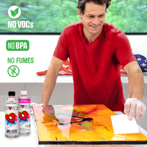 A man in a red shirt uses a white tool to coat a colorful canvas with 32 Oz (946 Ml) ArtResin Epoxy Resin. Two ArtResin bottles marked “NO VOCs,” “NO BPA,” and “NO FUMES” sit nearby, with an American flag in the background.