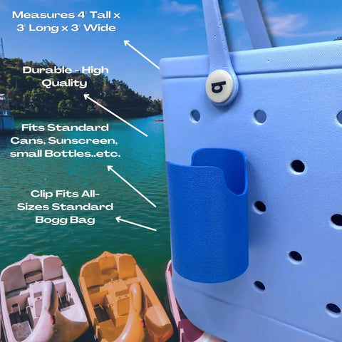 Close-up of a blue bag with the FRESHe BAGLETS Can Drink & Water Bottle Holder Charm Accessory by Chatelet Manufacturing, 4x3x3, attached. Fits bottles/cans, all Rubber Tote Bags; compatible with Bogg Bags. Boats on water in background.