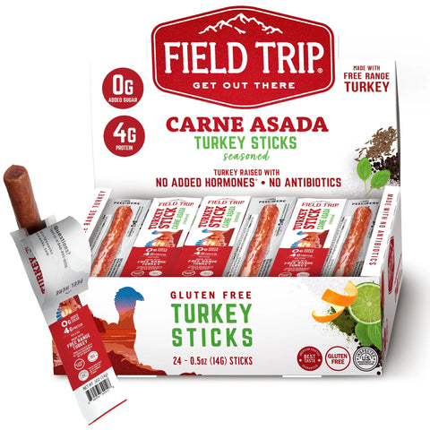 A box of Field Trip Carne Asada Turkey Stick 0.5oz (24ct), gluten-free with 0g added sugar and 4g protein per stick, made from free-range turkey. One stick is partially unwrapped and displayed upright on the left.