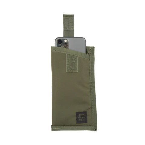A gray smartphone is partially tucked into the olive EW Soft Case by MIS, featuring a Velcro strap and stitched MIS MADE IN USA label. This versatile pouch, ideal for sunglasses, is shown against a white background.