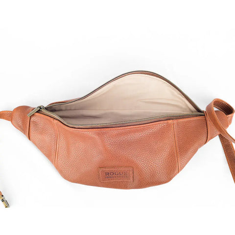 The Crescent Leather Sling Bag by Rogue Industries is a brown full-grain leather crossbody with a zipper, featuring a beige fabric interior and the embossed Rogue Industries logo on the front.