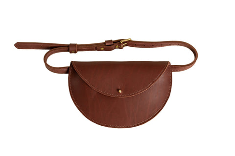 The Urban Southern Half-Moon Belt Bag is a brown full-grain leather accessory with a rounded flap, gold button closure, and adjustable strap, handcrafted in the USA and shown on a white background.