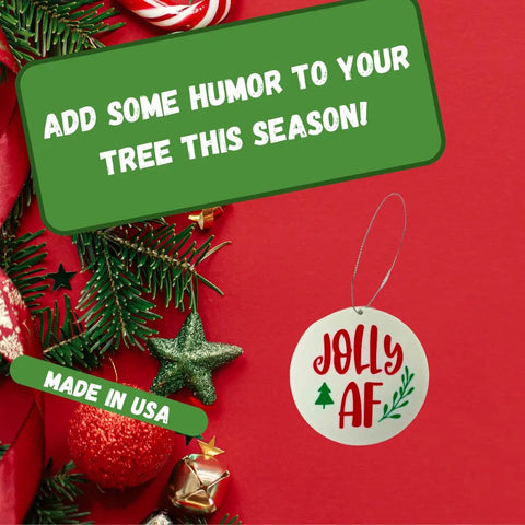 A festive flat lay featuring Chatelet Manufacturing’s Funny Gag Gift Christmas Ornament that reads “Jolly AF,” with pine branches. Green text boxes say ADD SOME HUMOR TO YOUR TREE THIS SEASON! and MADE IN USA—a great Dirty Santa or gag gift.