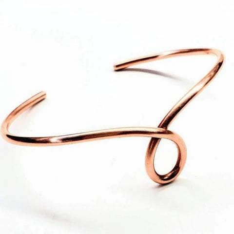 The Handmade Copper Teardrop Bangle by Alexa Martha Designs features a minimalist, polished wire with an elegant looped front design. This adjustable bracelet is shown against a white background.