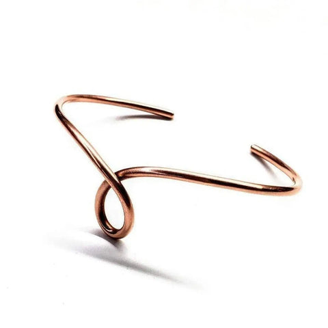 The Handmade Copper Teardrop Bangle by Alexa Martha Designs is a minimalist, handcrafted bangle from Montana with a central loop and asymmetrical open ends, shown on a white background.