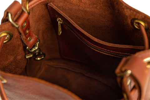 Close-up of the Urban Southern Urban Bucket Bag interior, featuring gold hardware, a zipper pocket, and suede lining; handcrafted in the USA.