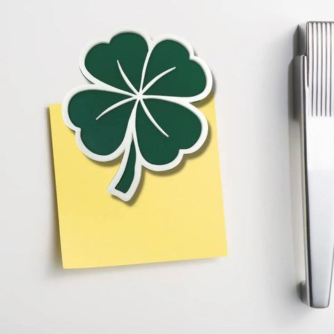 The Chatelet Manufacturing Saint Patricks Day Lucky Shamrock Fridge Magnet holds a yellow sticky note on a white surface, with a silver stapler on the right—adding festive flair to your space for Saint Pattys Day. Made in the USA.