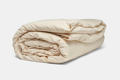 The American Blossom Linens Cotton Duvet Cover Set, in light beige and finely constructed, is neatly folded and displayed against a plain white background.