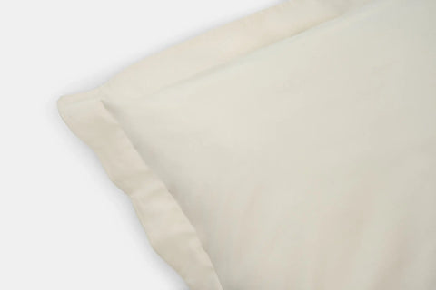 A close-up of the American Blossom Linens Cotton Duvet Cover Set displays its smooth, soft cream fabric and neatly stitched edges, highlighting quality craftsmanship against a plain white background.