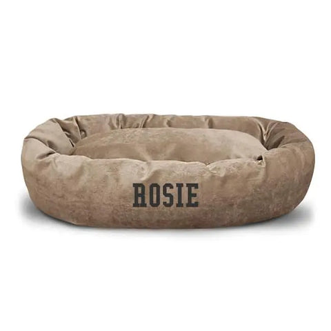 The Majestic Pet Villa Bagel Dog Bed - Personalized features soft Polyester Micro-Velvet in brown and has “ROSIE” printed in bold black letters on the front.