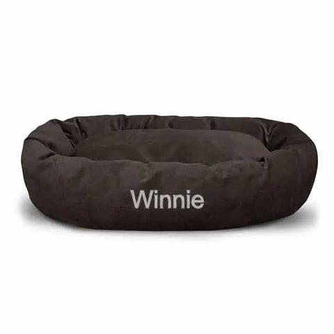 A round, dark brown Villa Bagel Dog Bed by Majestic Pet, personalized with Winnie embroidered in white letters on the front.