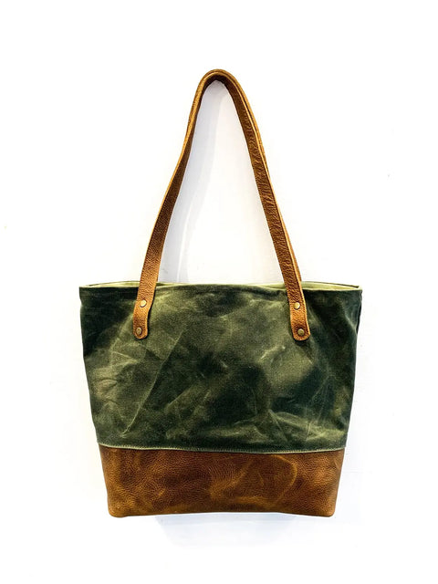 The Saco River Tote Bag by Rogue Industries features olive green waxed canvas on top, brown full-grain leather on the bottom, two brown leather shoulder straps, and a minimalist design.