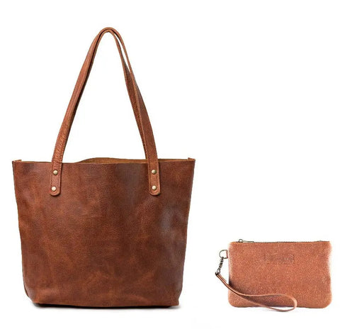 A Sebago Leather Clutch by Rogue Industries, featuring a wristlet strap and classic design, sits beside a large brown leather tote with shoulder straps. Both made in the USA and crafted for timeless style.