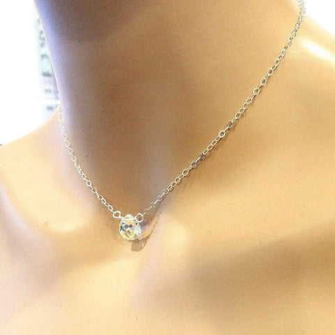 A close-up of a person’s neck wearing the Sterling Silver Wire Wrapped Crystal Briolette Drop Necklace by Alexa Martha Designs—an elegant bridesmaid jewelry choice with its delicate, sparkling crystal pendant.