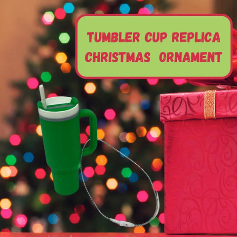 The Chatelet Manufacturing Tumbler Cup Replica Christmas Ornament hangs in front of a decorated tree and red gift box—an ideal 2023 popular water bottle replica mug holiday ornament, made in the USA, for unique Christmas decor.