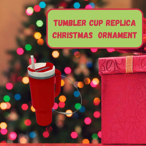 A Tumbler Cup Replica Christmas Ornament by Chatelet Manufacturing hangs before a festive tree, beside a pink gift box. This 2023 popular water bottle mug ornament is perfect for unique holiday decor and is made in the USA.