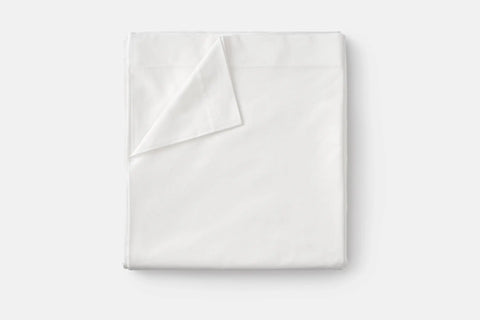 A neatly folded Cotton Single [Separate] Flat Bed Sheet by American Blossom Linens, made from luxurious 100% USA grown cotton, with one corner turned down, displayed on a plain light background.