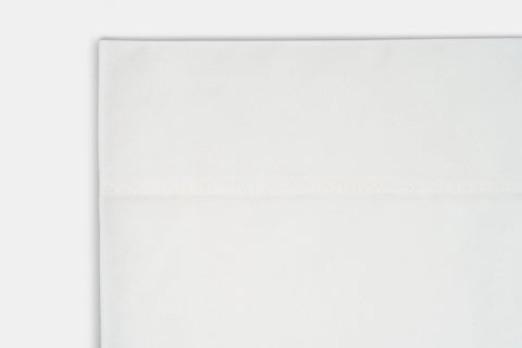 A close-up of the Cotton Percale Bed Sheet Set by American Blossom Linens, neatly folded with a visible horizontal seam, set against a white background to showcase its luxurious feel and premium quality.