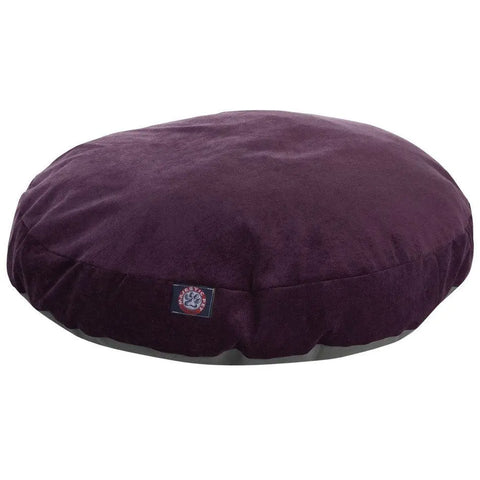 The Majestic Pet Villa Round Dog Bed is a dark purple, velvety cushion with a small side patch label and a washable, removable cover, perfect as a stylish round pet bed against a plain white background.