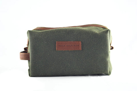 The Rogue Industries Waxed Canvas Dopp Kit features green waxed canvas with brown leather accents and handle, a stitched Rogue Industries label, and is proudly made in the USA. Displayed against a plain white background.